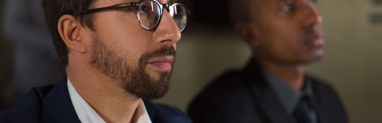 Businessman in eyeglasses working in dark office. Close-up view of serious multiethnic business colleagues working late at night, selective focus. Working late concept