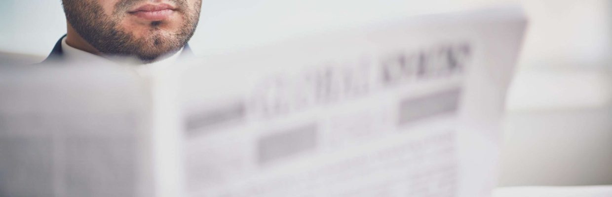 A young serious businessman reading newspaper