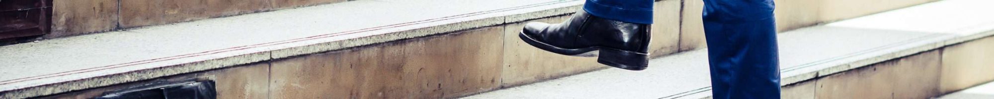 Close up of young businessman walking upstairs outside office. Close up of young businessman walking upstairs outside office.