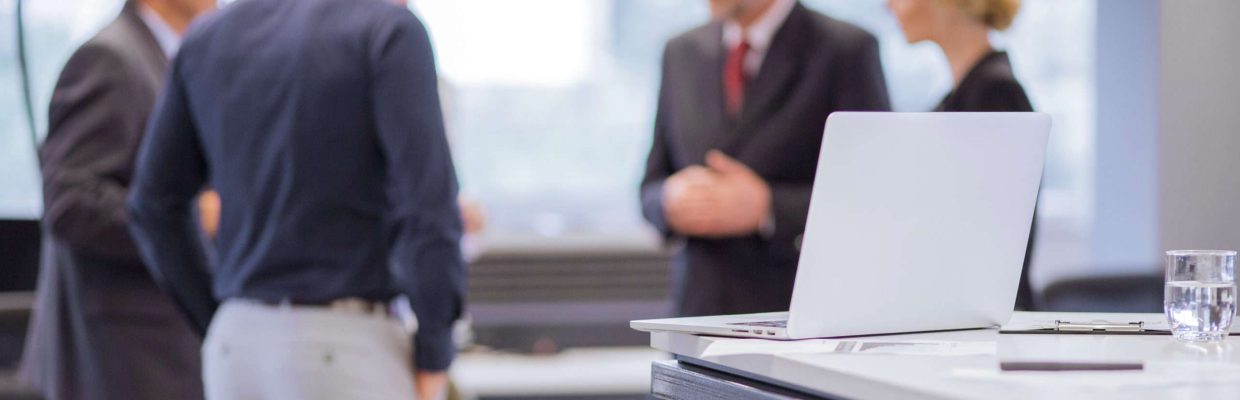 gruppo-uomini-d'affari-in piedi-davanti-tavolo-portatili